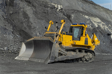 A bulldozer cleans a gold mine site in an open pit.