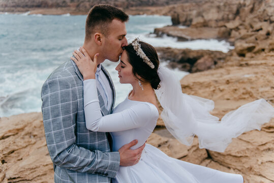 Romantic photo of newlyweds in love embracing on the background of the landscape of Cyprus sea and rocks
