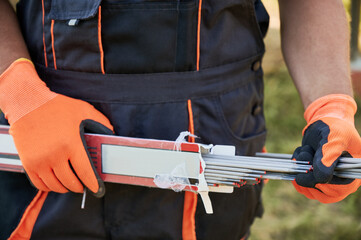 Close up of man hands in work gloves holding welding electrodes. Male builder with coated metal...
