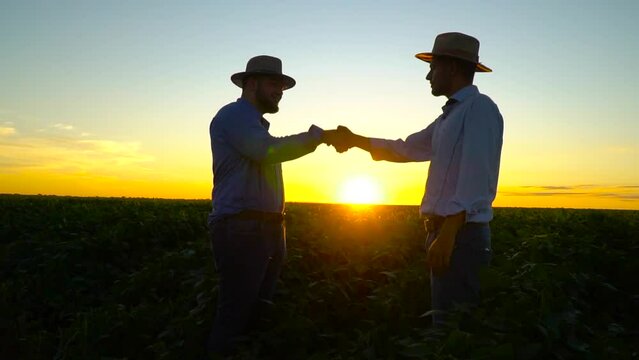 HANDS SHAKE IN SUPER SLOW MOTION AT SUNSET IN THE SOYA FIELD