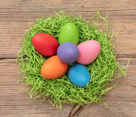 Easte pastel color egg in a nest on wood table background, overhead view