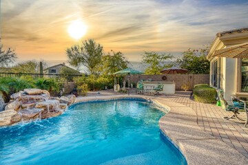 Luxury home pool at sunset with a waterfall - obrazy, fototapety, plakaty