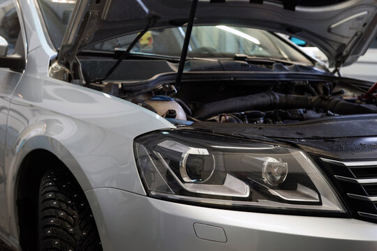 Close-up showing the front of a modern car. The hood of the car is open. Headlight. Car service, repair, auto parts. Selected focus.