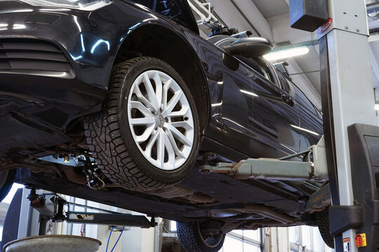 Moscow Russia - January 2022: Modern luxury car in a car service on a lift. Service, repair, diagnostics. Selected focus.