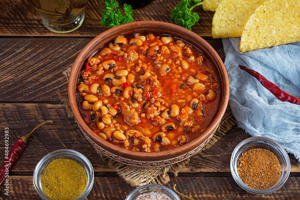 Wall mural Chili con carne in a bowl on wooden background. Mexican cuisine