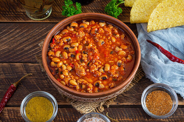 Chili con carne in a bowl on wooden background. Mexican cuisine