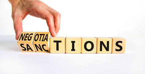 Sanctions or negotiations symbol. Businessman turns cubes, changes the word sanctions to...