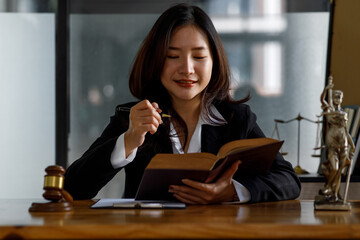 A Female lawyer in suit at the workplace with laptop, gavel and femida in office, Lawyer office Statue of Justice with scales and lawyer working on a laptop. Legal law, advice and justice concept.
