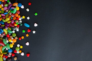 Colorful candies on black background, copy space for text or messages