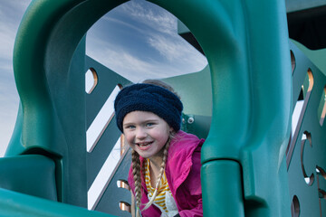 Young girl with a big smile playing on a jungle gym