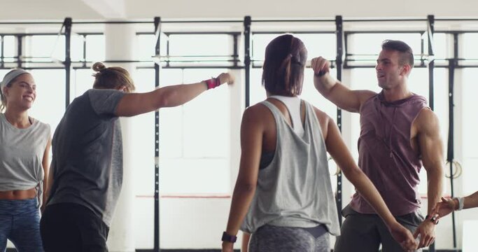 Giving each other that extra push. Fitness group of young people in a huddle joining hands. Sporty young people celebrating success and winning after training in a gym