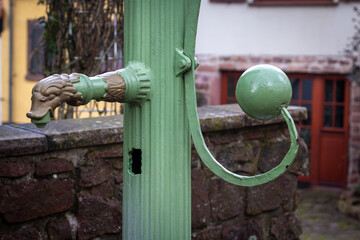 old decorated manual water pump made of green painted cast iron on a public square in a small old town in southern germany