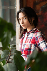 young beautiful woman on a pose in the studio, standing in a plaid shirt