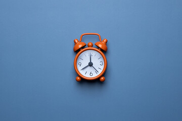 Orange retro alarm clock on a blue background