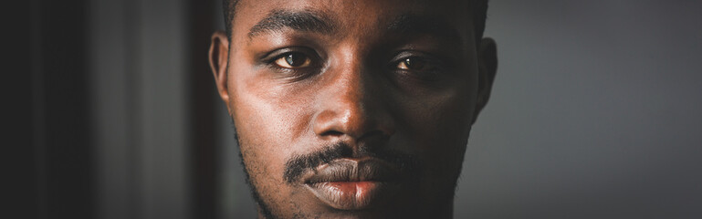 Obraz premium Depressed African man thinking about disappointed love and looking down in dark room.Concept of Broken Heart and Valentine's Day