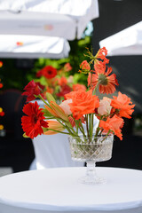 Colorful flower in crystal vases on a white table. Outdoors