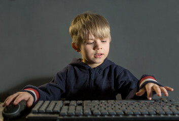 the boy learns to use the computer, he presses the buttons on the keyboard