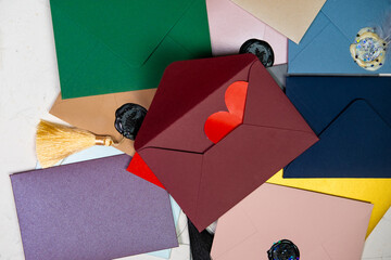 Red heart in an envelope. Lots of colorful envelopes. Envelopes sealed with wax. Correspondence, valentine's day concept.