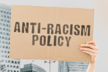 The phrase " Anti-Racism Policy " on a banner in hand. Human holds a cardboard with an inscription. Equality. Multicultural. Nationality. Law. Legislation. Human rights