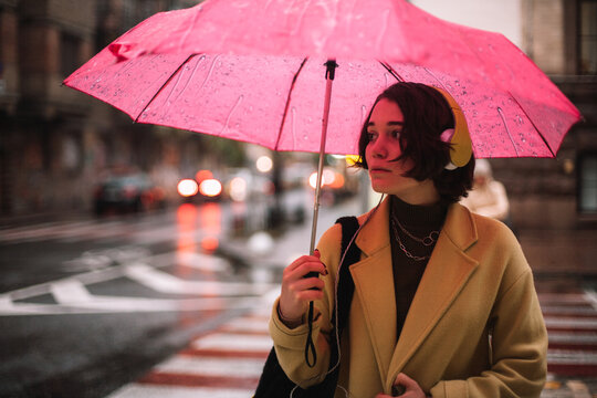 Young woman with an umbrella standing on street in city in autumn