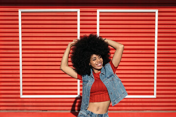 Young afro woman posing over a red background