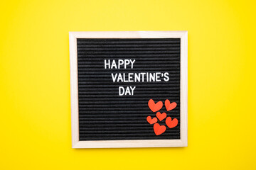 Happy valentine's day, text on yellow background top view.