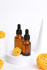 Amber glass dropper bottles different sizes on podium on white background with rattan balls. Cosmetic container mock-ups. Background for branding and packaging presentation.