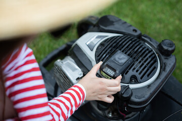 Close-up view of a woman removing the battery from a garden mower.