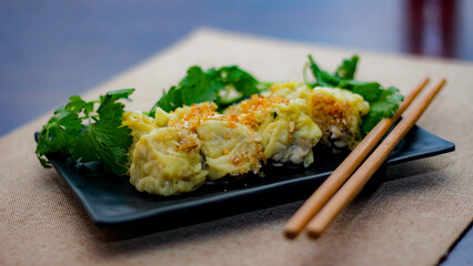Chinese Steamed Dumpling served in a black plate on a wooden table. along with cilantro.