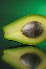 Avocado on a mirrored surface with a green background