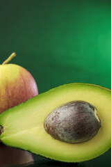 Avocado with apple on a mirrored surface with a green background