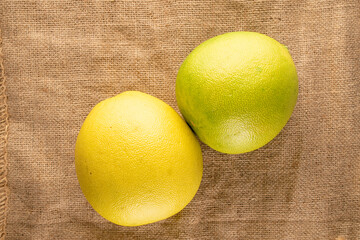 Two juicy organic pomelos on sackcloth, macro shot, top view.

