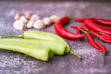 Red chilli and green chilli, garlic spread on the gray table ready to cook in the kitchen.