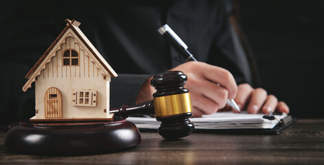 Judge gavel and house model on the table. Man signing in document. Real Estate Lawyer