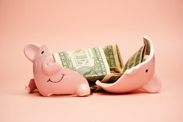 Broken piggy bank with coins money on pink background