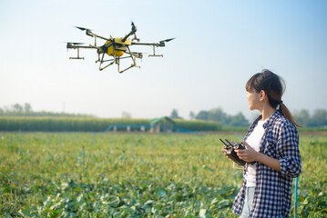 Young smart farmer controlling drone spraying fertilizer and pesticide over farmland,High...