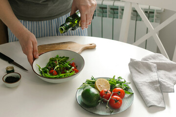 Woman preparing vegetable salad with tomato in the kitchen. Healthy food vegan salad