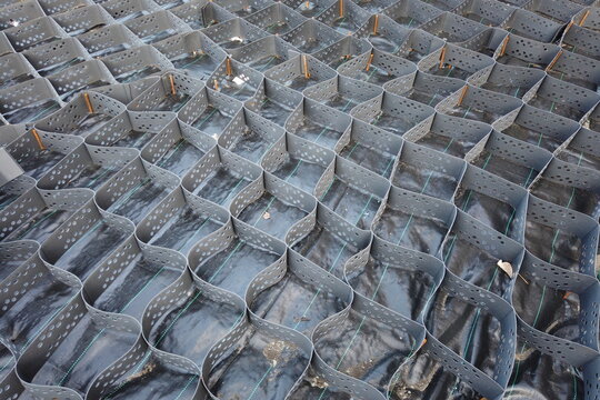Park road made of geogrid between lawns with green grass. Closeup. Diagonal