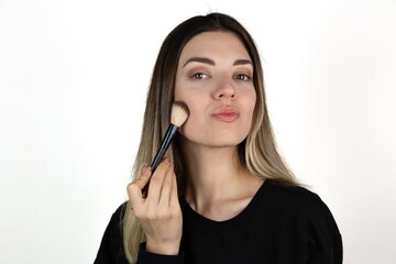 Photo of young girl with flawless skin holding cosmetics brush on white background. Skin care and beauty concept. 