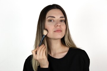 Young girl with flawless skin holding cosmetics brush on white background. Skin care and beauty concept.	