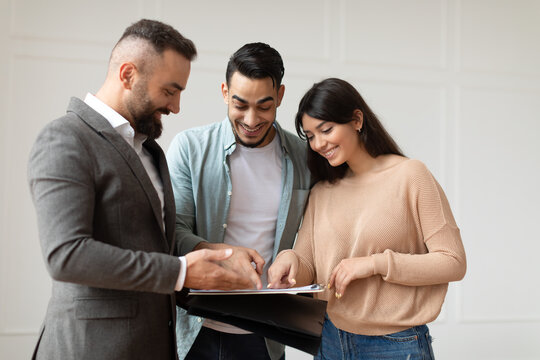 Couple Buying New Apartment, House Agent Showing Documents Blueprints