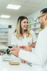 Obraz premium Happy young male and female colleagues pharmacist working in a pharmacy