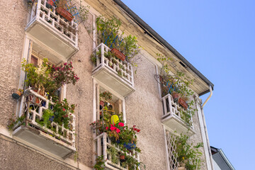 Fototapeta na wymiar European street. French balcony. Flowers on windows and balconies. Facade of a residential building. Travel in Europe.