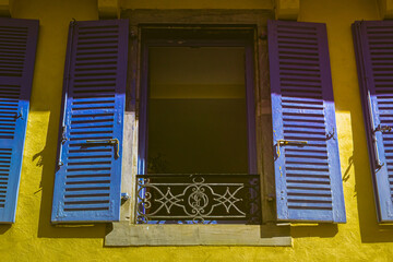 European street. Wooden shutters. Facade of a residential building. Travel in Europe. Open and closed shutters. French windows.
