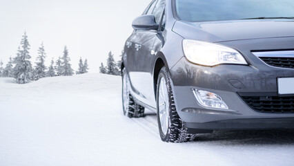 Fototapeta na wymiar Car on the Winter Road. Close-up Image of Winter Car Tire on the Snowy Road. Safe Driving Concept.