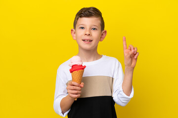 Little caucasian boy with a cornet ice cream isolated on yellow background pointing up a great idea