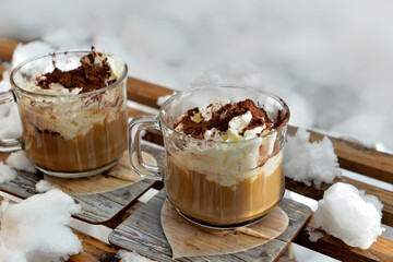 two cups of cappuccino placed on a wooden sled in the  snow