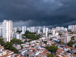 Naklejka premium Dramatic drone aerial view of summer rain clouds in Pompeia neighborhood buildings and houses in São Paulo city before storm and flooding in the streets. Concept of climate crisis, weather, thunder.