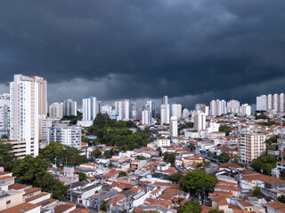 Fototapeta na wymiar Dramatic drone aerial view of summer rain clouds in Pompeia neighborhood buildings and houses in São Paulo city before storm and flooding in the streets. Concept of climate crisis, weather, thunder.