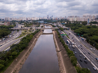 Fototapeta premium Beautiful drone aerial view of Marginal Tiete river avenue, Sao Paulo city skyline on summer sunny day. Cars, trees and buildings. Concept of urban, metropolis, architecture, pollution, climate.